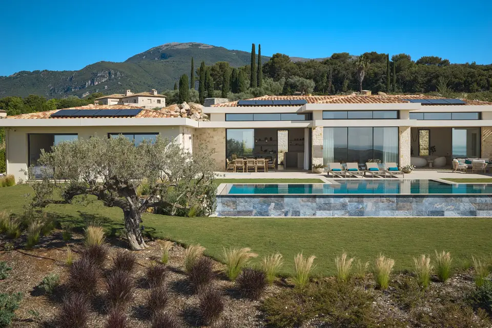 Single-storey villa with stone pillars, full-height glazing and an infinity pool facing the hills.