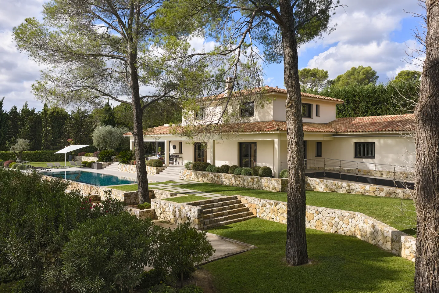 Villa et jardin en terrasses soutenus par des murets en pierre, piscine sur la gauche