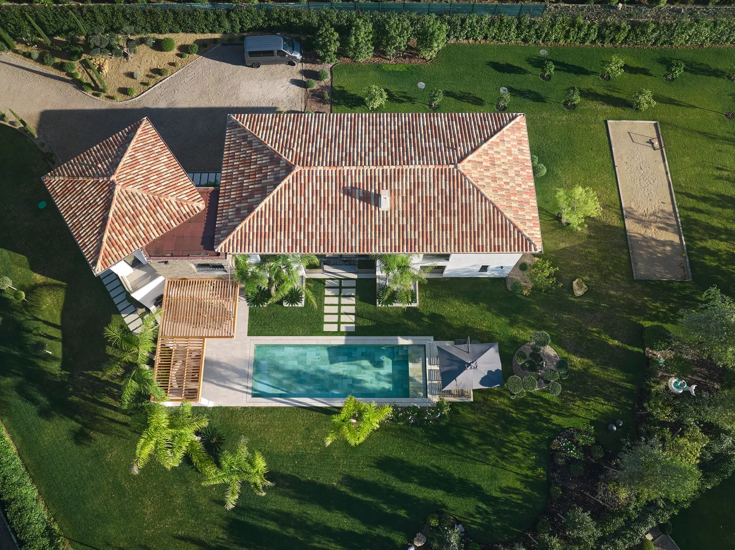 Vue zénithale : toiture en tuiles, piscine, pergola et terrain de pétanque dans le jardin
