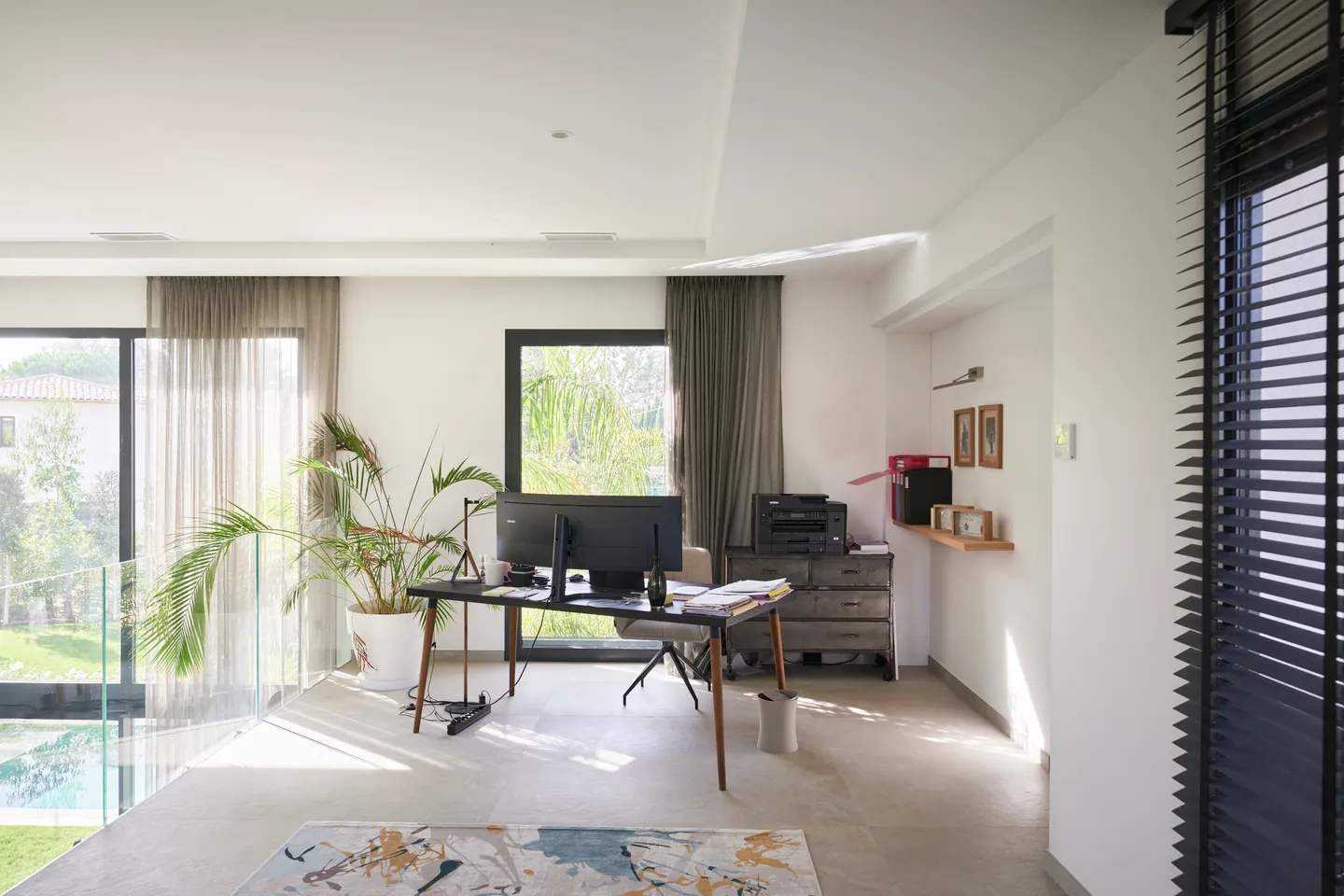 Coin bureau lumineux à l'étage, palmier en pot et baies vitrées sur le jardin