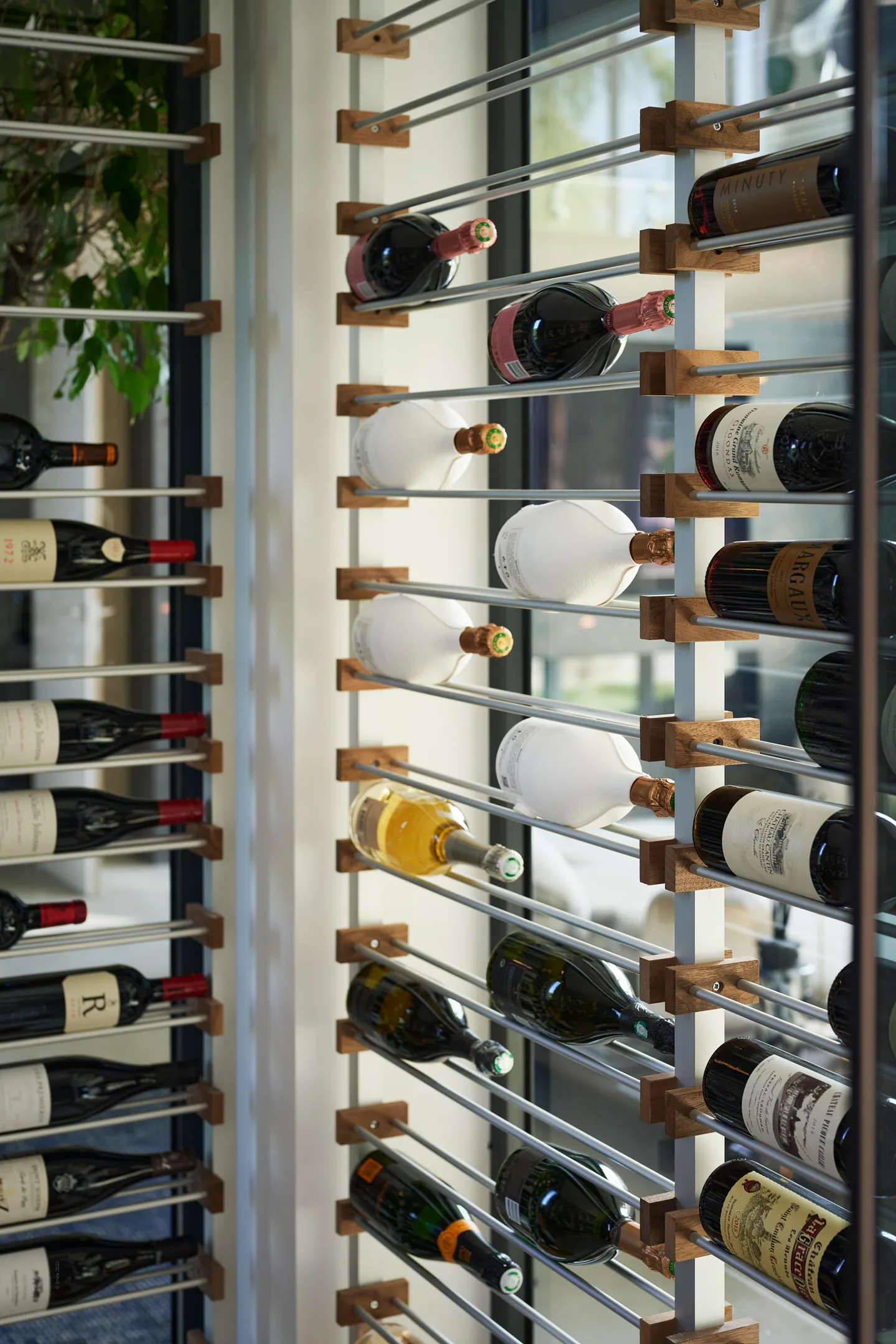 Bouteilles de vin rangées sur un cellier mural à tiges métalliques et taquets en bois