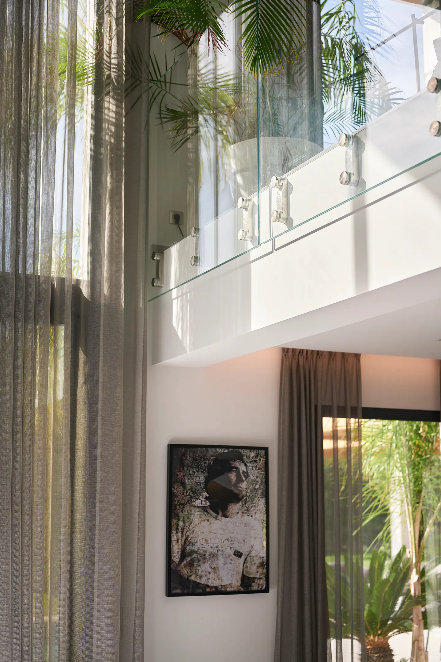 Rideaux voilés et mezzanine vitrée en double hauteur, portrait encadré au mur