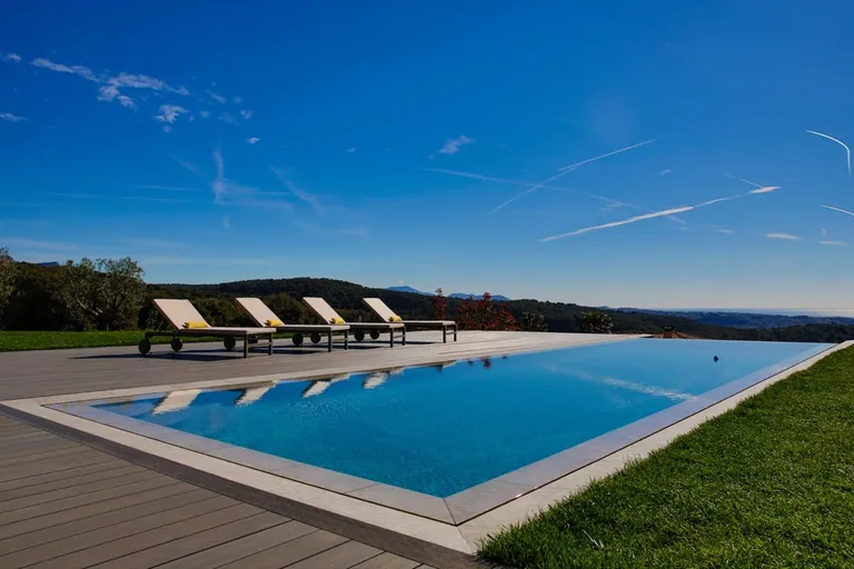 Piscine, bains de soleil et pelouse sous un ciel bleu