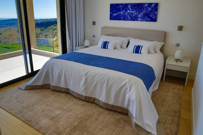 Chambre parentale avec lit double et baie vitrée ouverte sur la terrasse