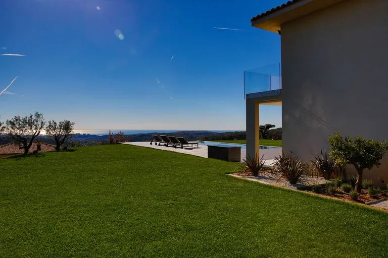 Pelouse, piscine et vue mer depuis le côté de la villa