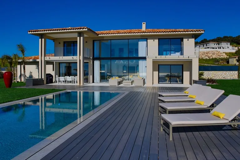 La villa vue depuis la plage de la piscine, bains de soleil au premier plan