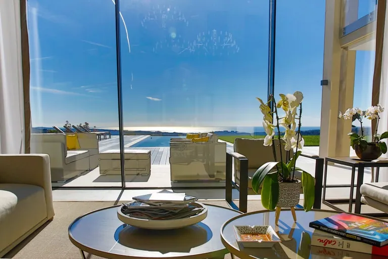 Vue depuis le salon sur la terrasse, la piscine et la mer