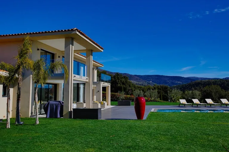 Angle de la villa avec terrasse, jarre rouge et piscine face aux collines