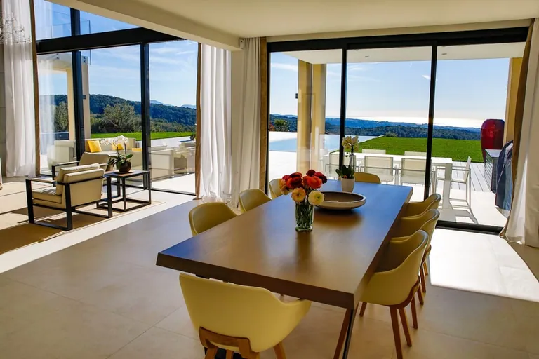 Salle à manger ouverte sur la terrasse, la pelouse et la vue mer