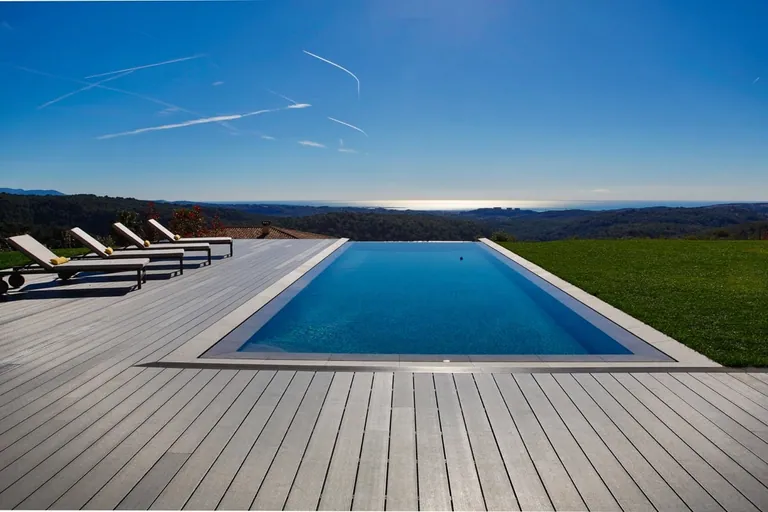 Piscine à débordement face à la mer et aux collines boisées