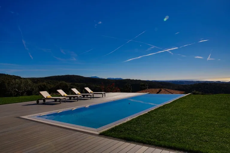 Piscine bordée de pelouse avec vue sur les collines