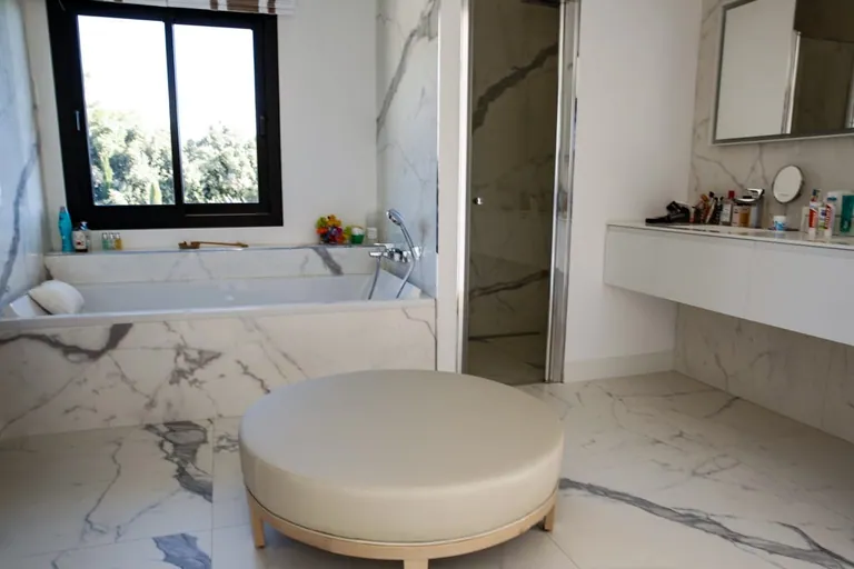 Salle de bains en marbre avec baignoire, douche et pouf central