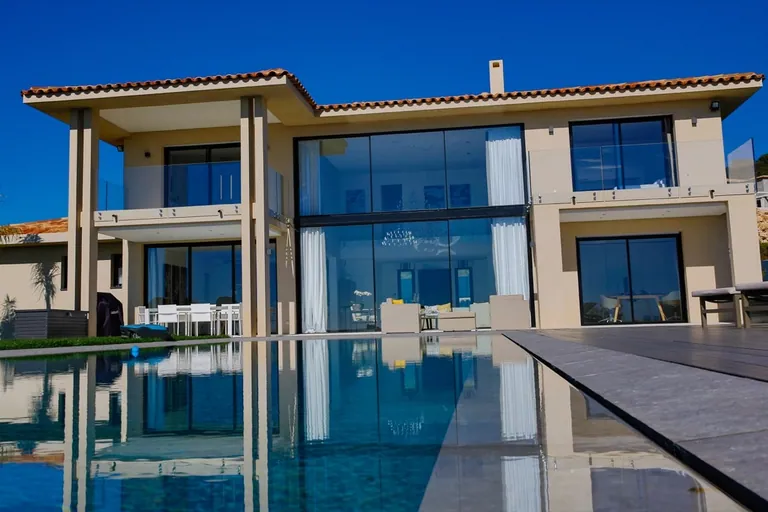 Façade vitrée vue au ras de l'eau, avec son reflet dans la piscine