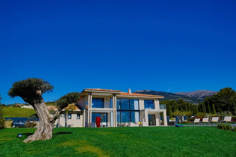 La villa au fond d'une vaste pelouse, avec un olivier taillé et les collines