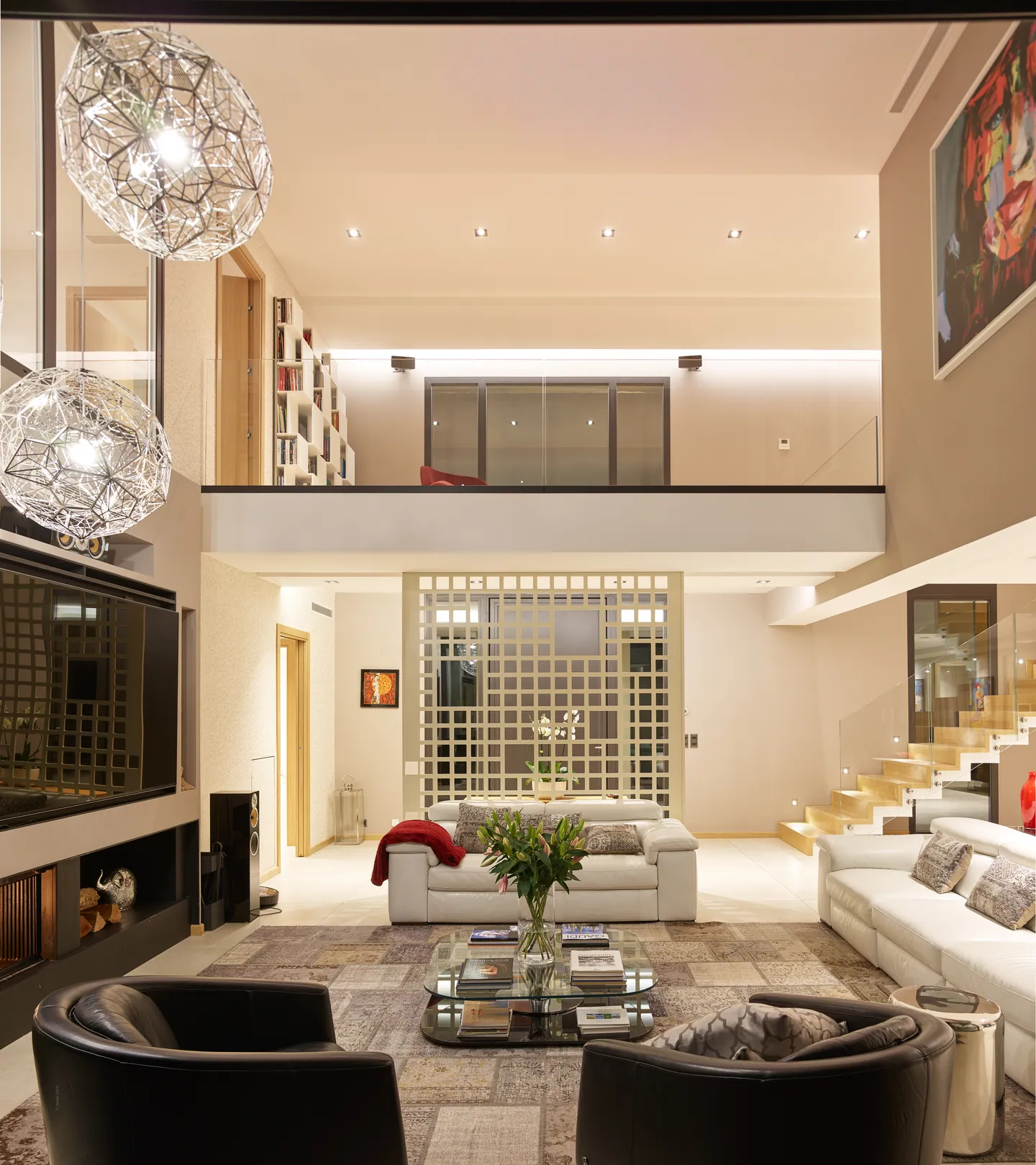 Lit double-height lounge with library mezzanine and metal pendant lights