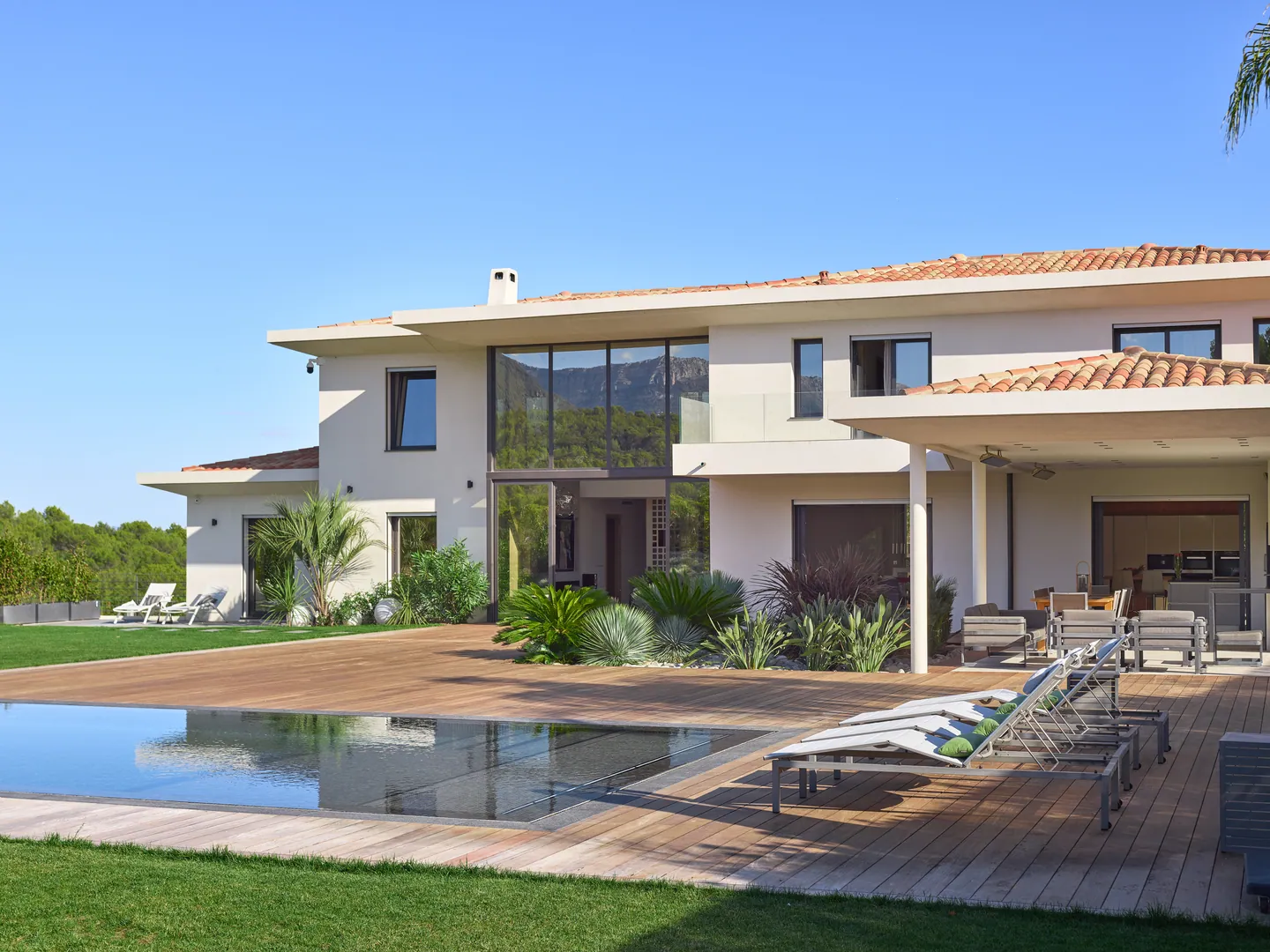 Timber deck with loungers by the pool, glazed facade behind
