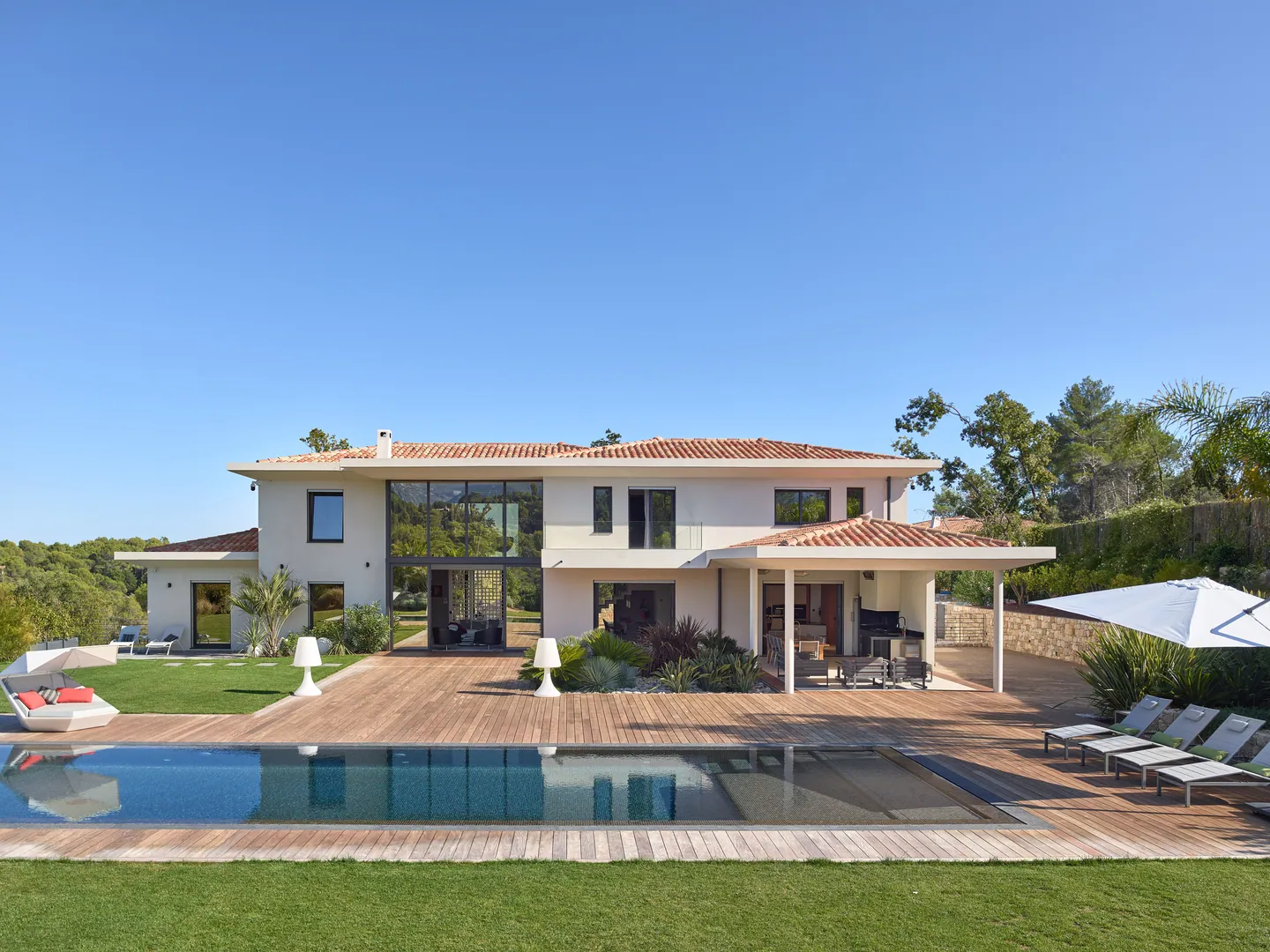 Villa côté jardin avec grande terrasse en bois et piscine miroir