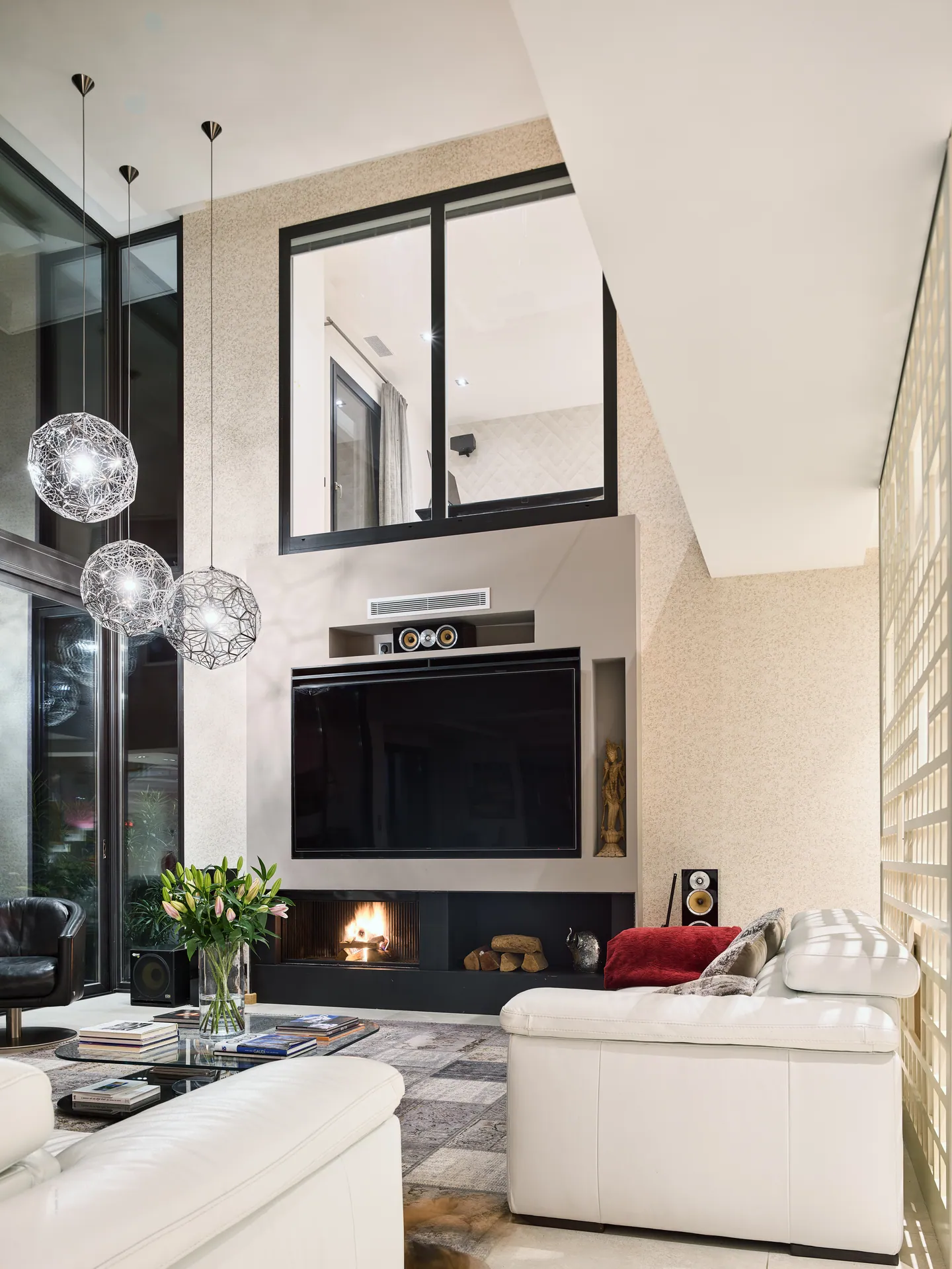 Double-height lounge in the evening, fire in the hearth and pendant lights