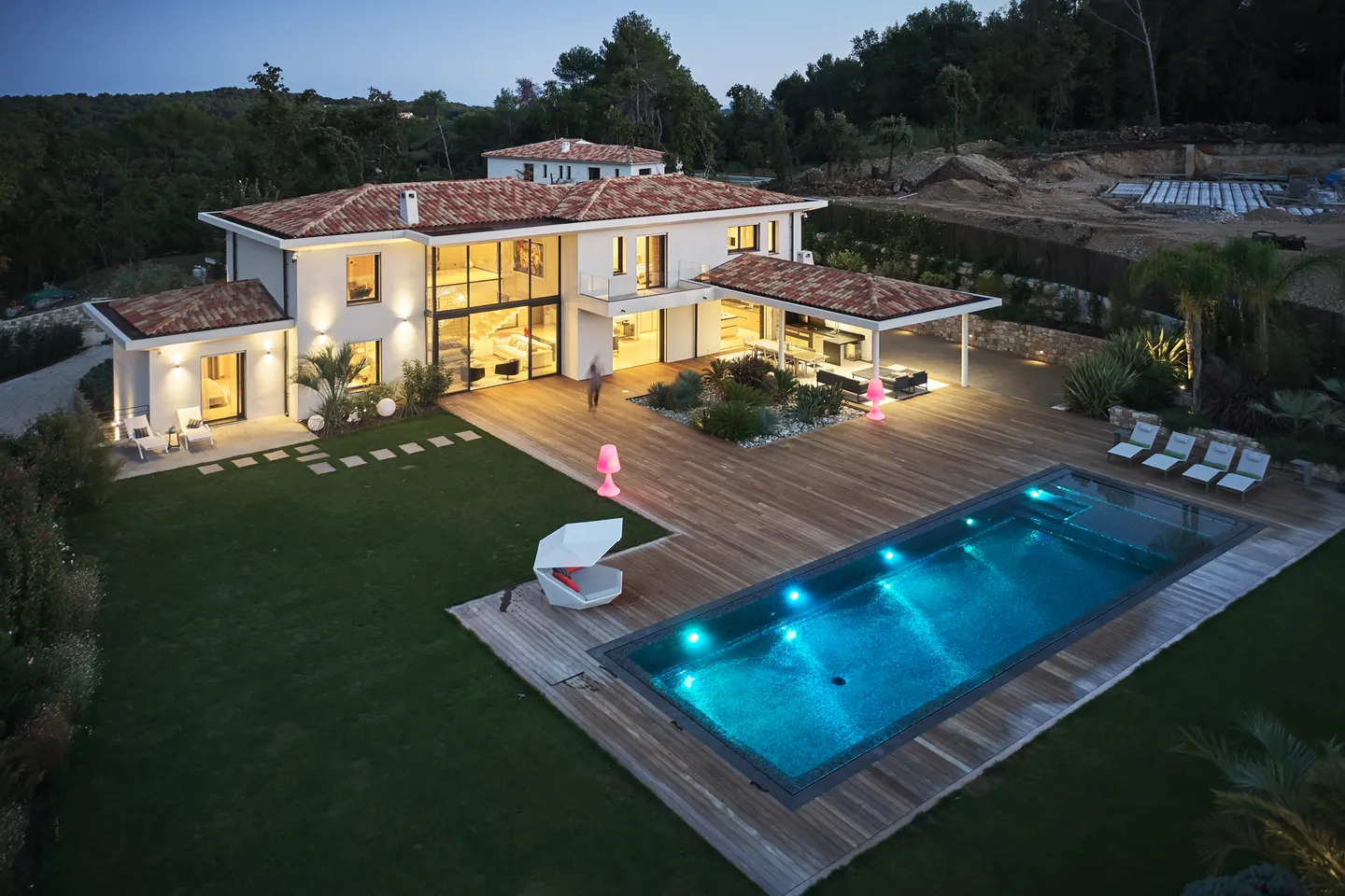 Aerial dusk view of the villa, deck and illuminated pool