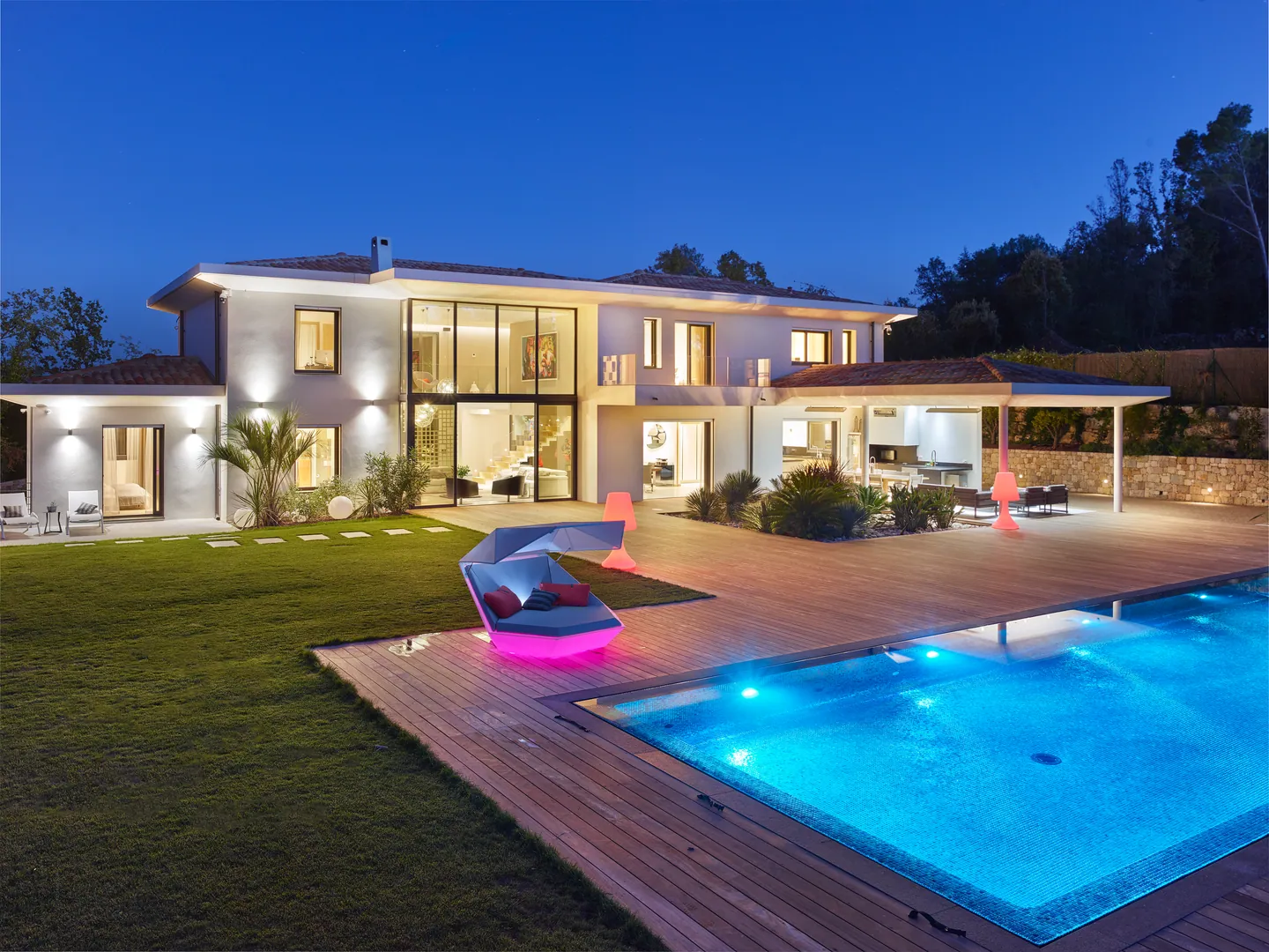 Timber deck and illuminated pool at blue hour, glowing daybed