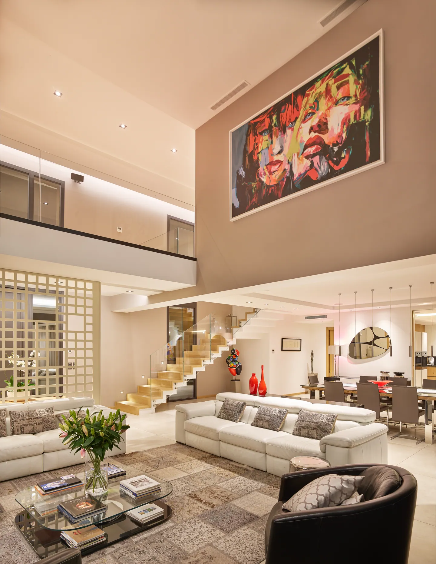 Cathedral-ceiling lounge with large painting, wooden staircase and dining area