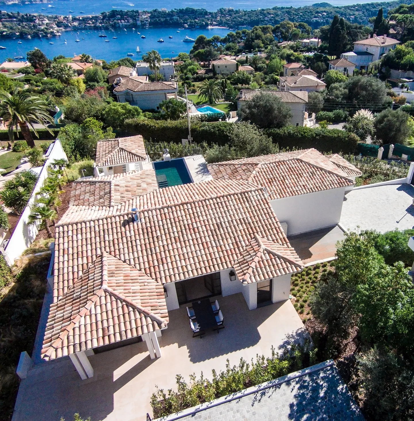 Aerial view of the tiled roofs, patio and covered terrace, sea in the background