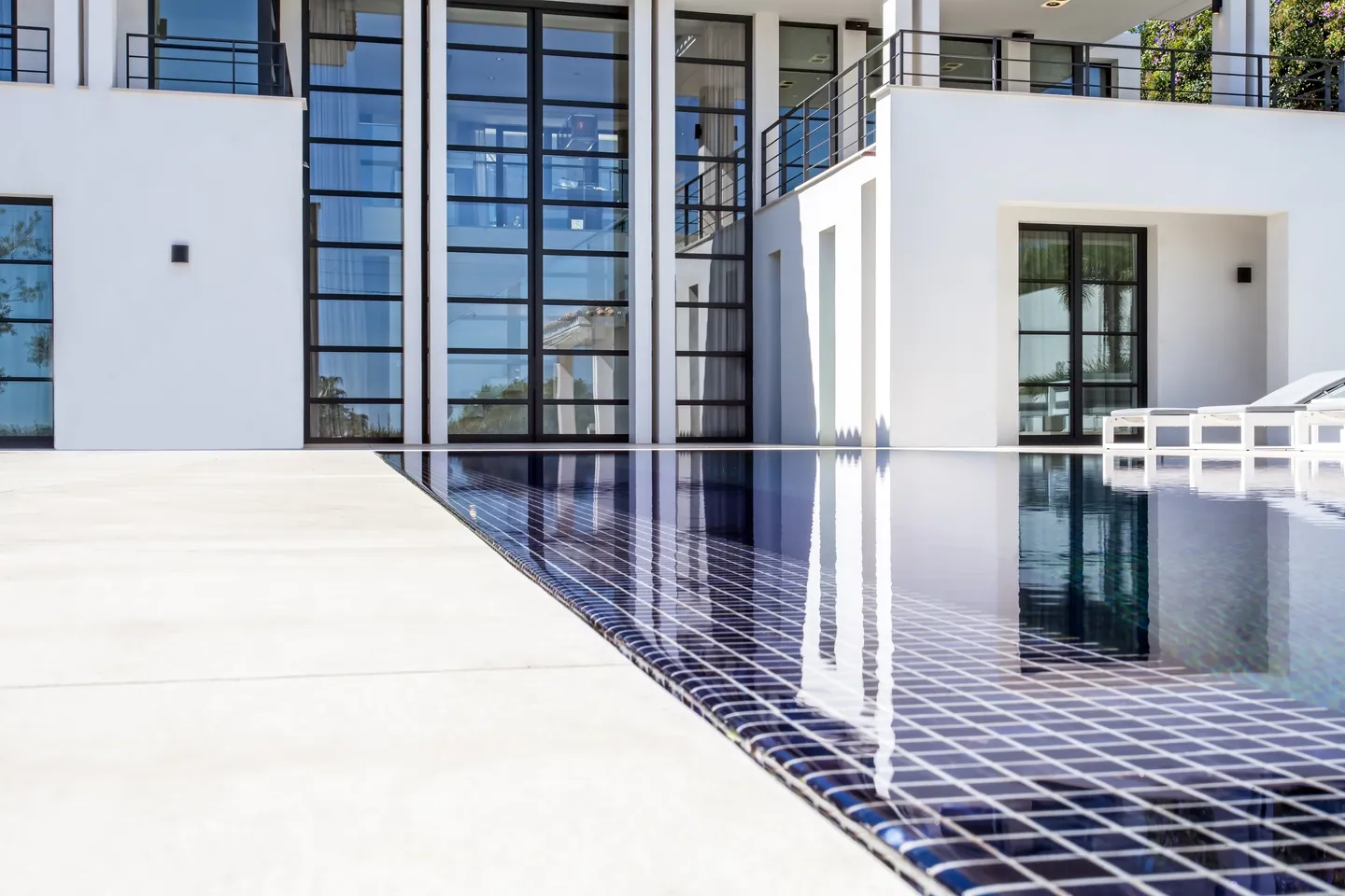 Navy mosaic pool edge reflecting the facade and its tall windows