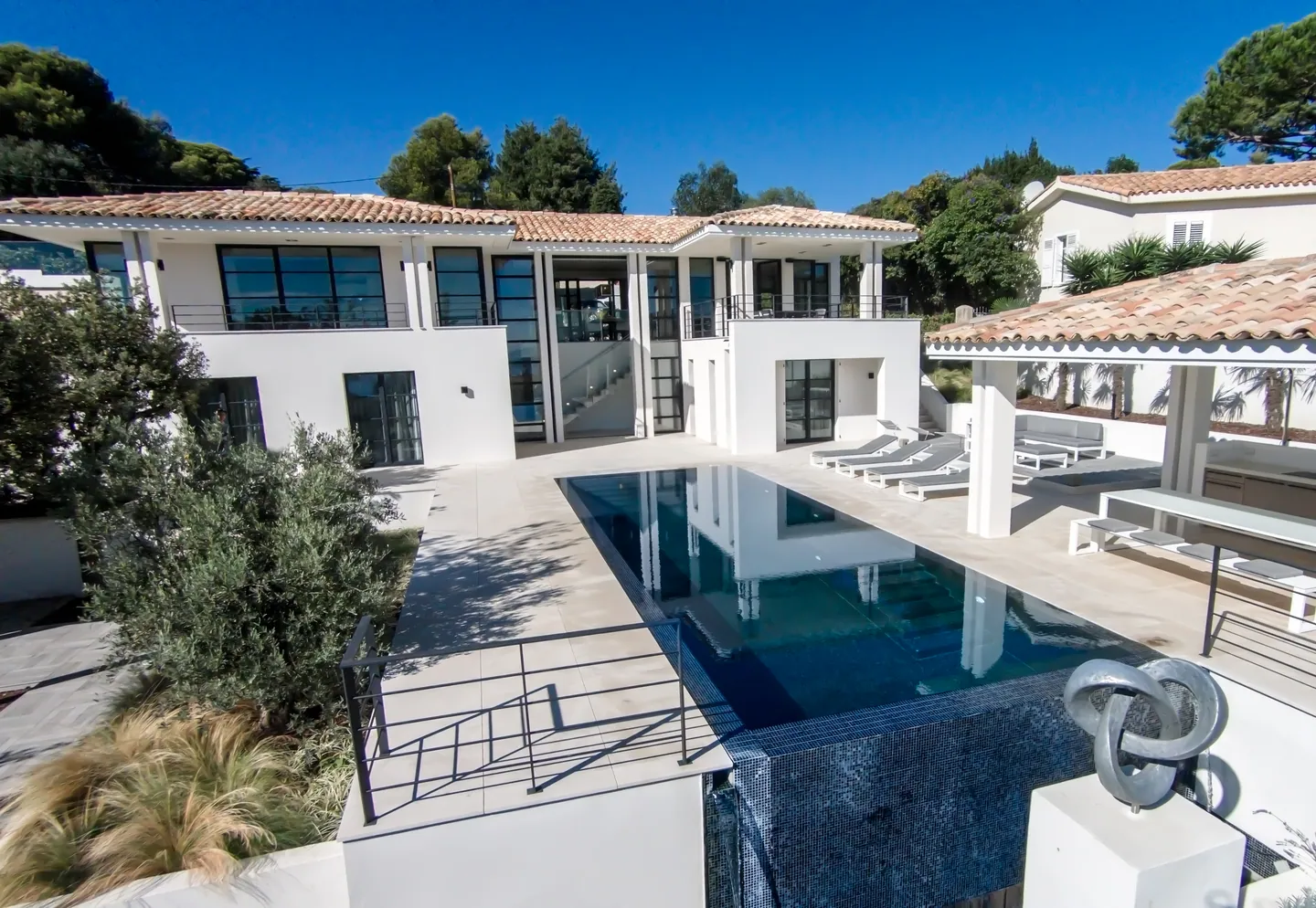 Villa seen from above with infinity pool, pool house and a sculpture