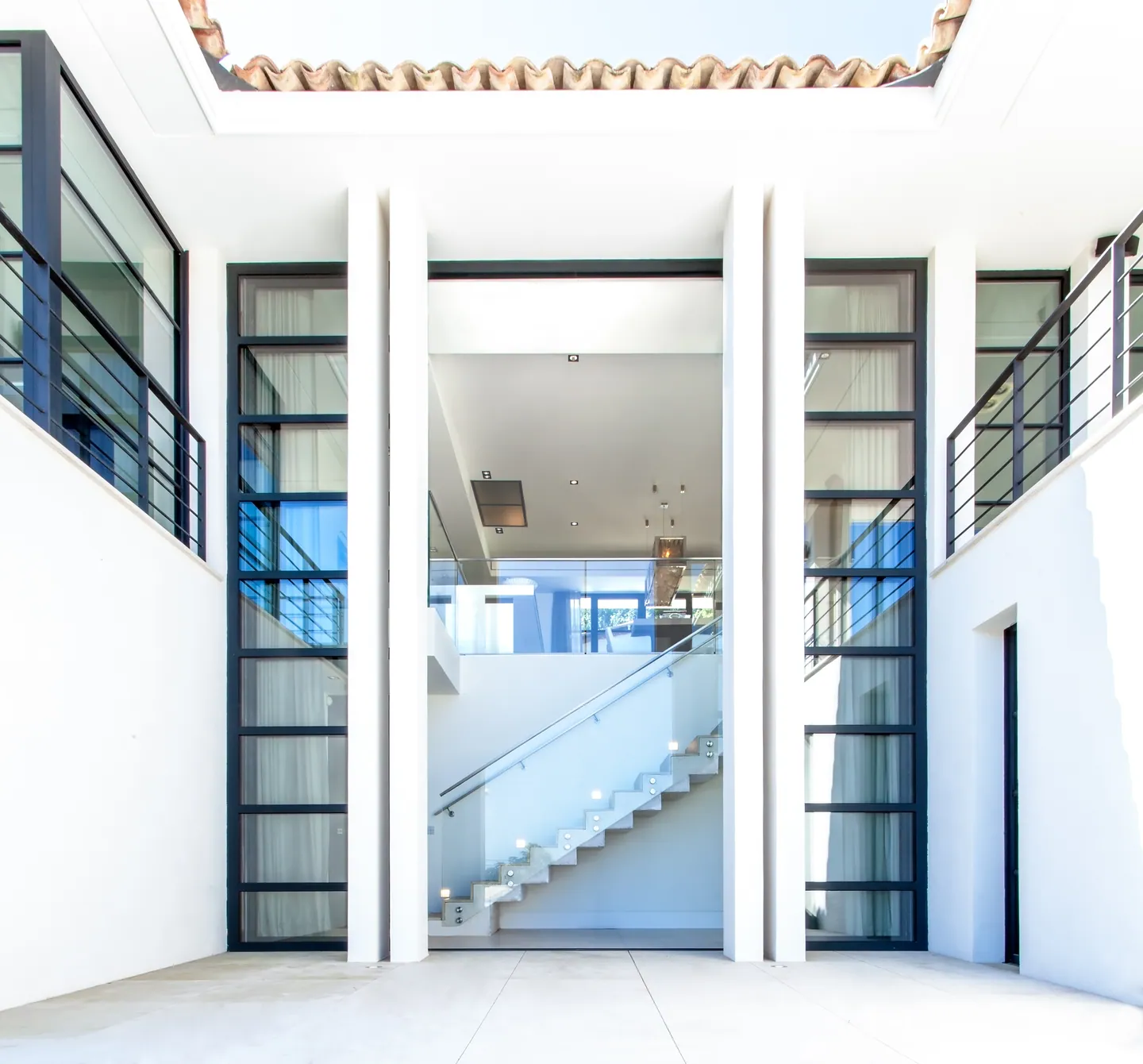 Double-height entrance framed by white pillars and glazing, staircase visible inside