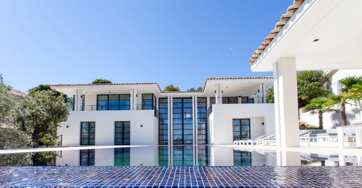 Glazed facade seen at water level across the blue mosaic infinity pool