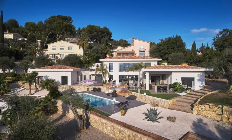 Contemporary villa with white rendered walls and stone cladding, pool and terraced garden, elevated view