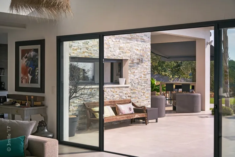 Living-room sliding door opening onto the terrace and its stone wall