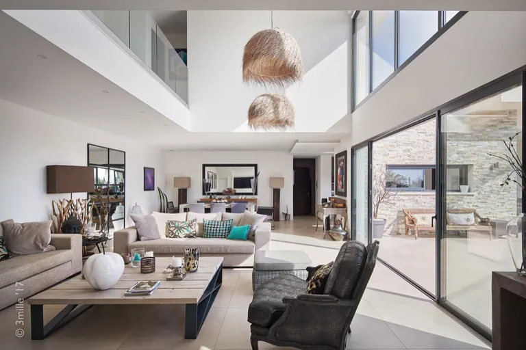 Double-height living room with glazed mezzanine, natural-fibre pendants and large glazed openings