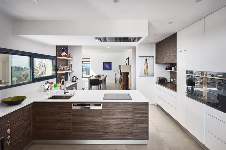 Open U-shaped kitchen in wood and white, looking towards the dining area