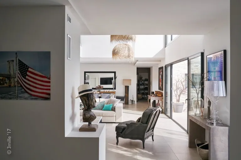 Approach to the sunlit living room, glazed doors open onto the terrace