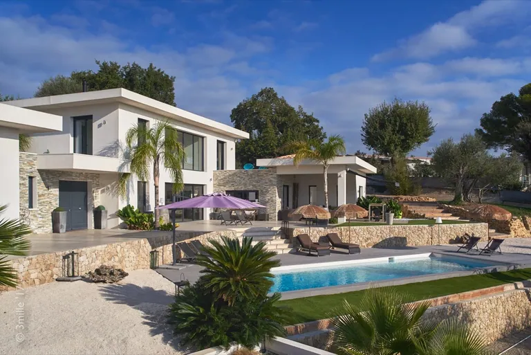 Pool, sun loungers and stone walls in front of the villa under a blue sky