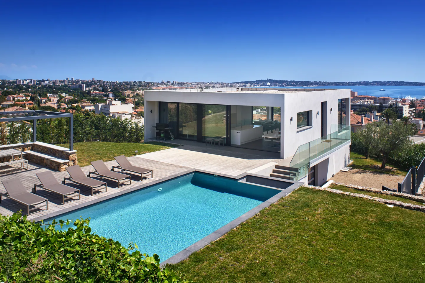 Villa contemporaine à toit plat avec piscine, transats sur deck et vue dégagée sur la mer
