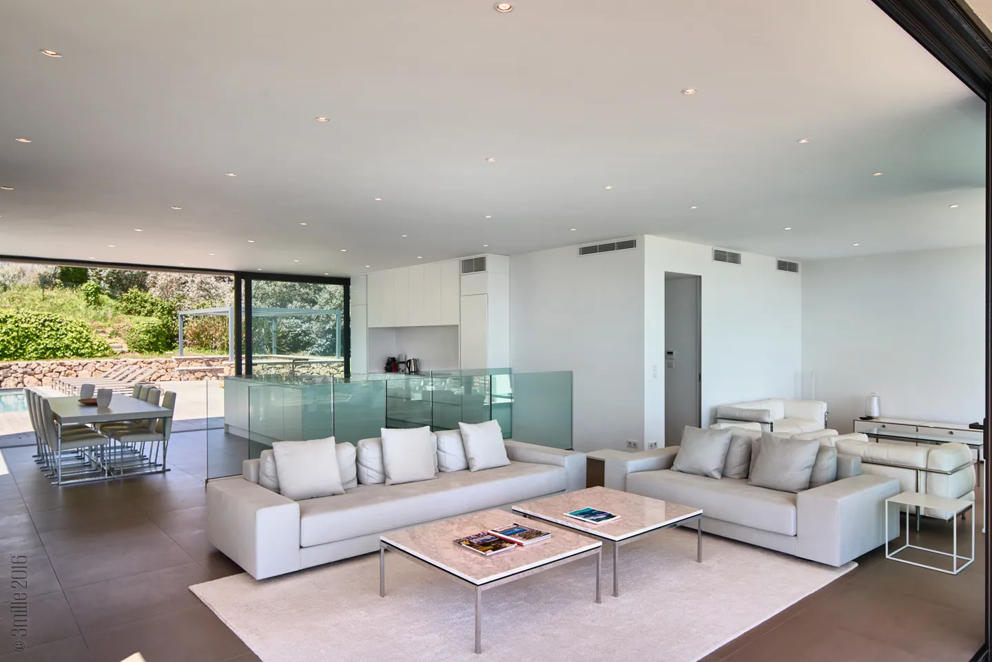 Open living room with white sofas, marble coffee tables and dining area by the pool