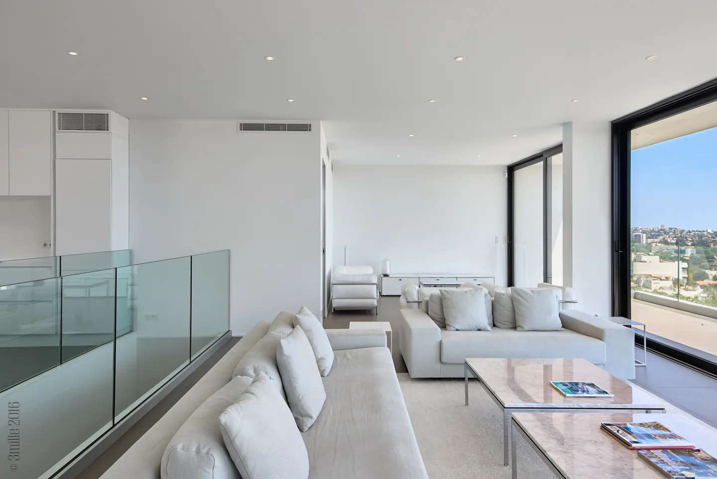 Lounge with white sofas, glass balustrade and window onto the open view