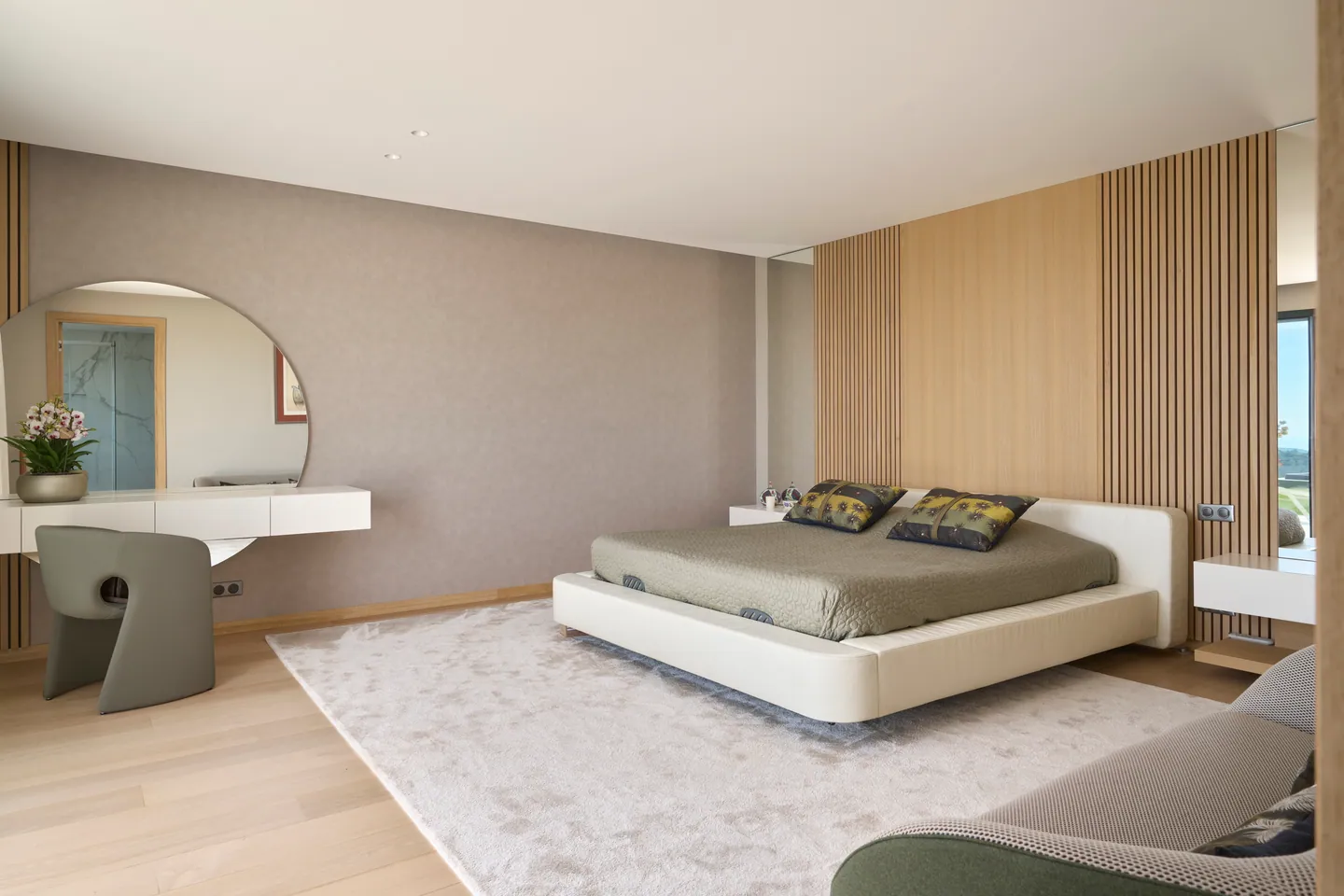 Chambre parentale avec coiffeuse et miroir rond, lit bas et paroi à lames de bois