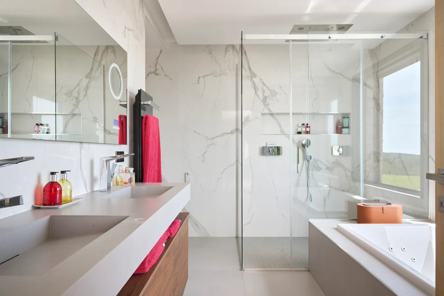 Salle de bains en marbre blanc veiné, double vasque, douche vitrée et baignoire