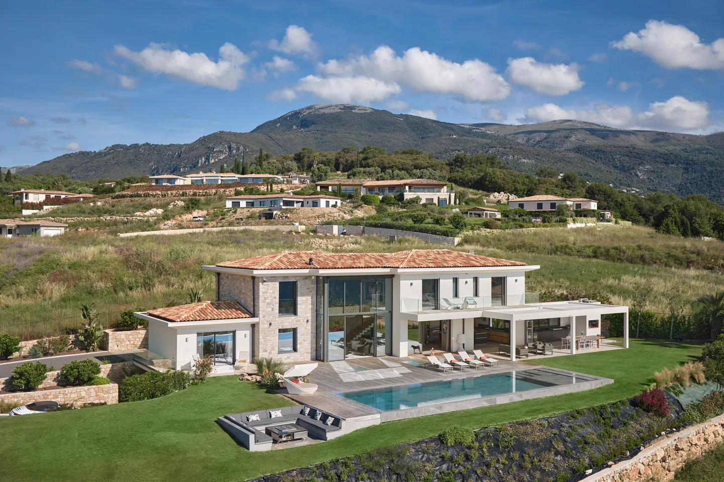 Vue aérienne de la villa, piscine à débordement et pelouse, montagnes en arrière-plan