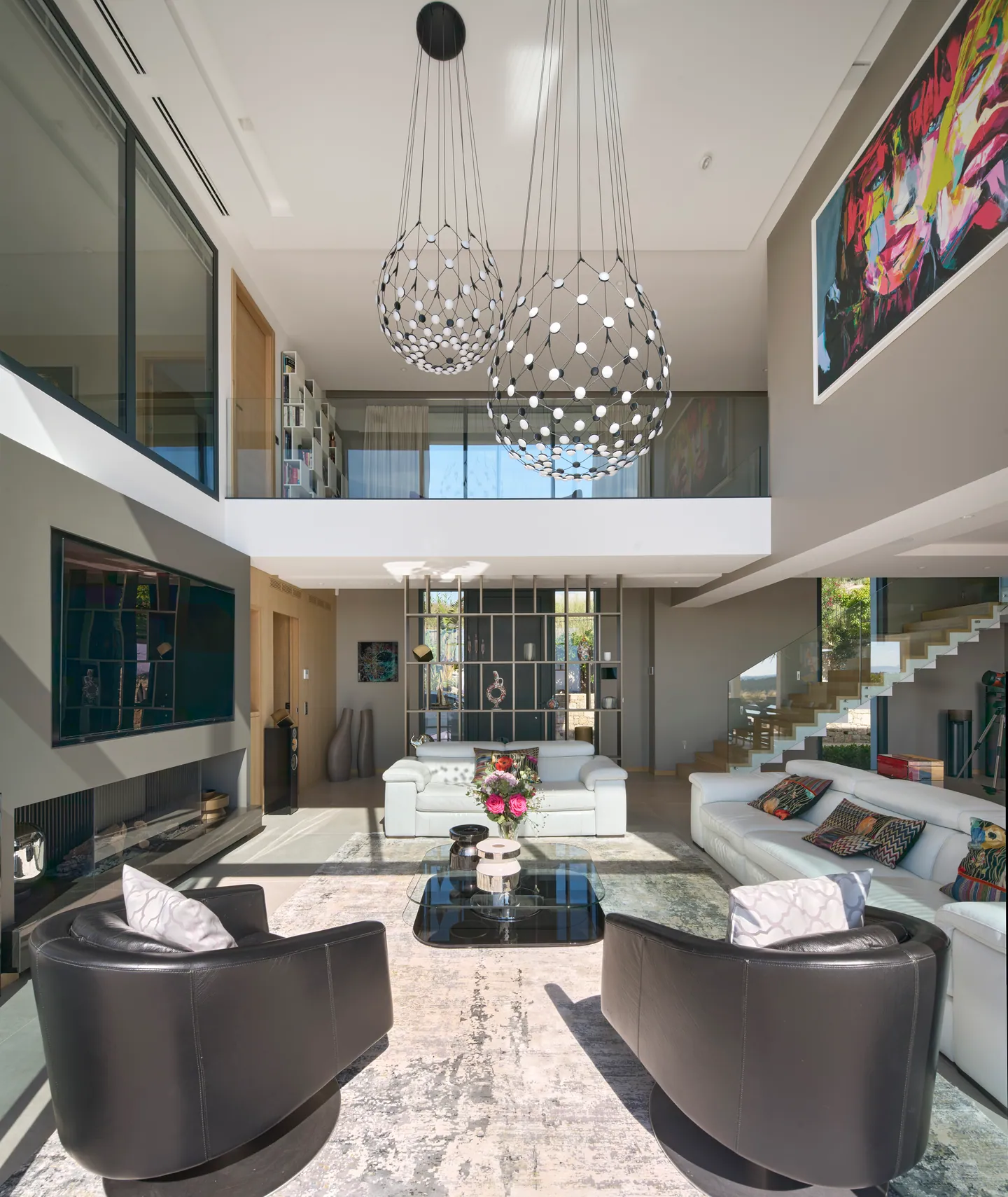 Salon sous mezzanine, canapés blancs, fauteuils en cuir et grand tableau coloré