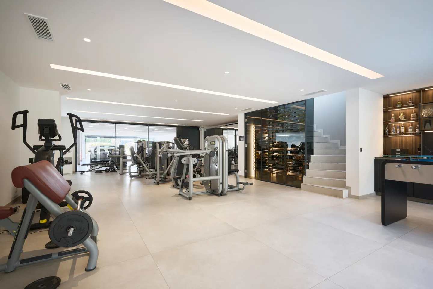 Salle de sport équipée, cave à vin vitrée et escalier en pierre claire