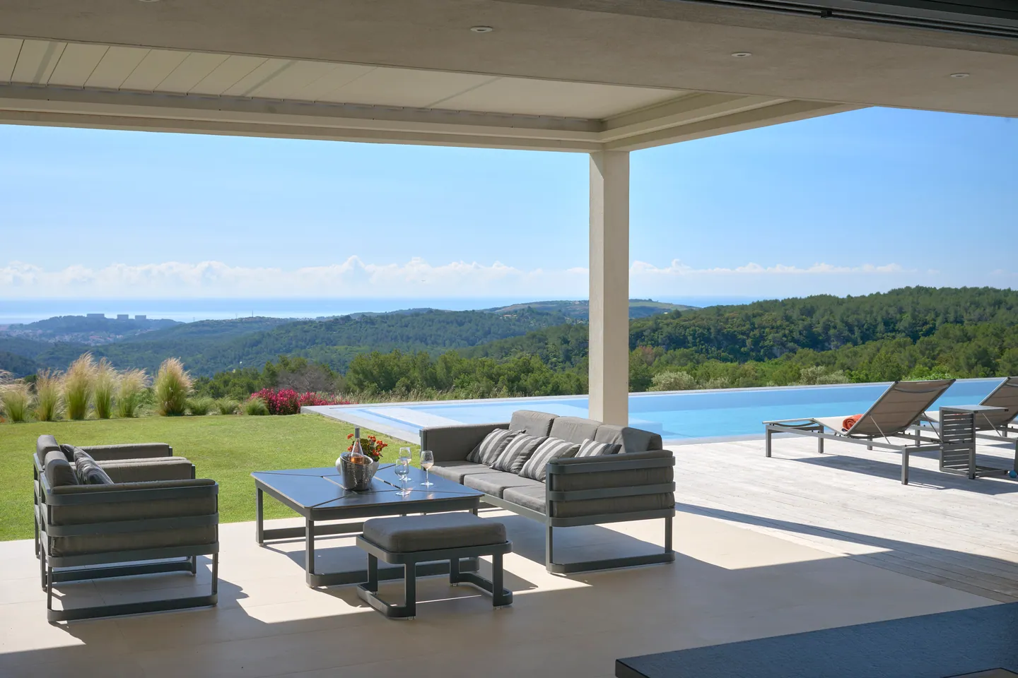 Salon extérieur sous terrasse couverte, piscine à débordement et vue mer