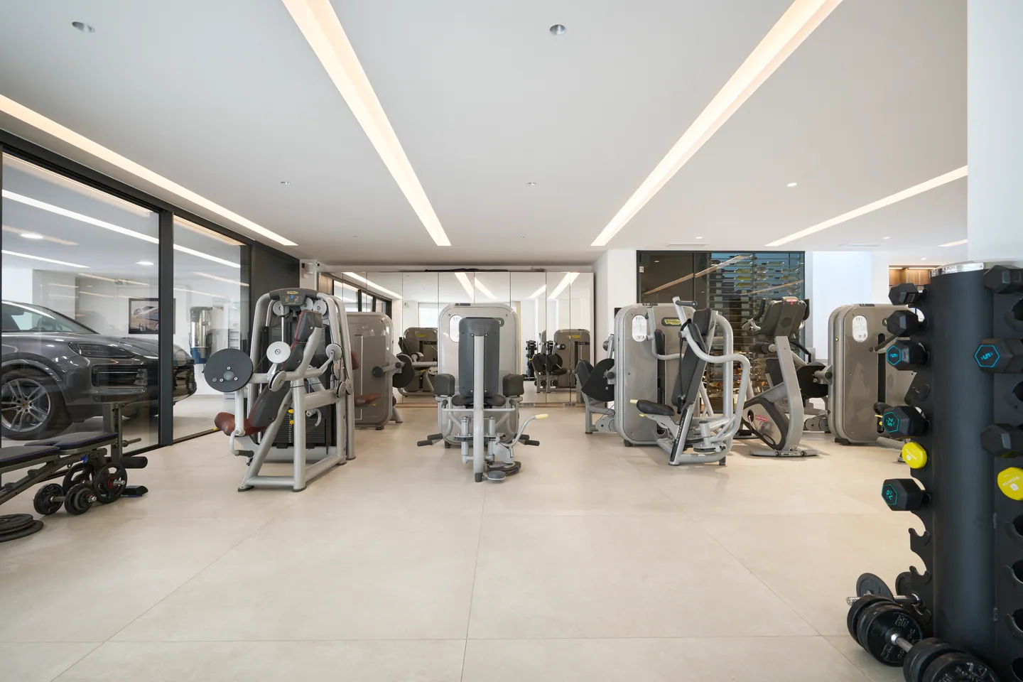 Salle de sport avec appareils de musculation et baie vitrée sur le garage