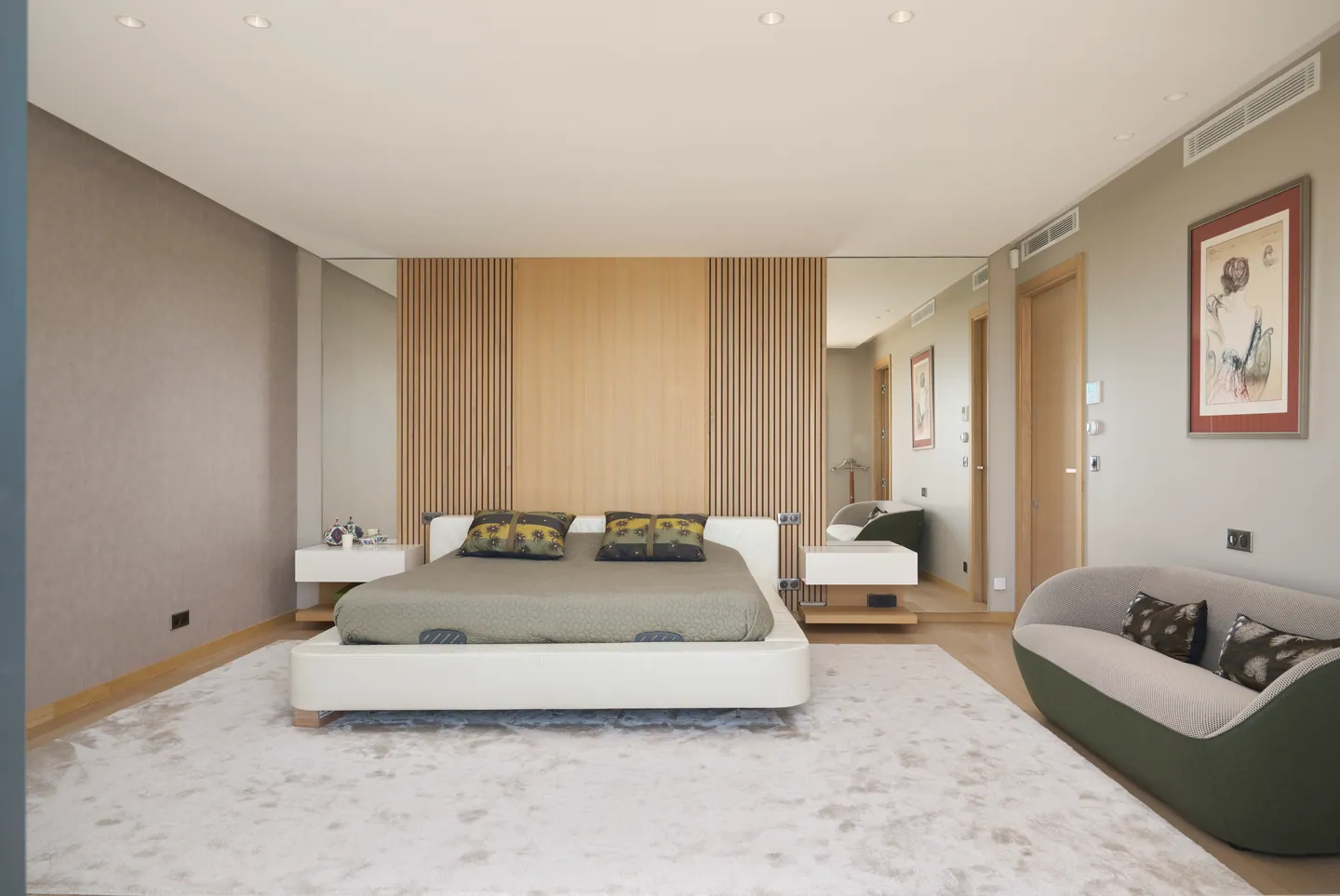 Chambre parentale, lit bas devant un mur à tasseaux de bois, tapis clair