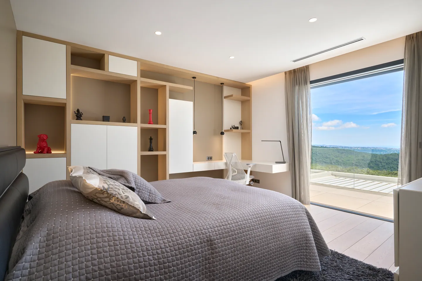 Chambre avec bibliothèque intégrée et bureau, baie vitrée sur les collines
