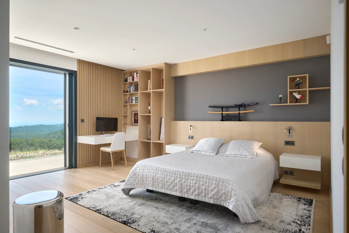 Chambre lambrissée de bois avec bureau et étagères, baie ouverte sur le paysage