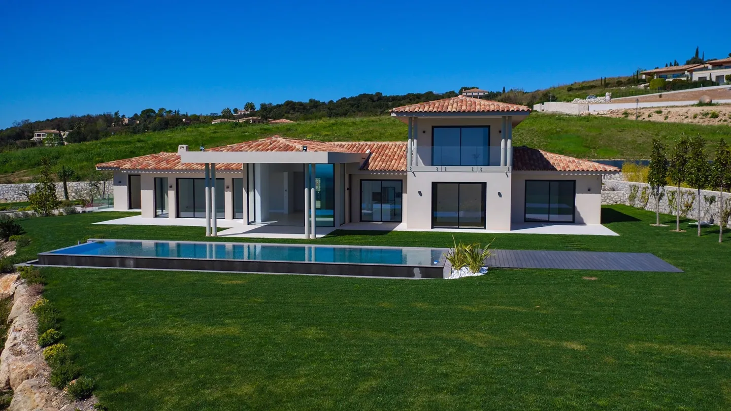 Villa with tiled roofs and a columned pergola, long pool in front of the lawn